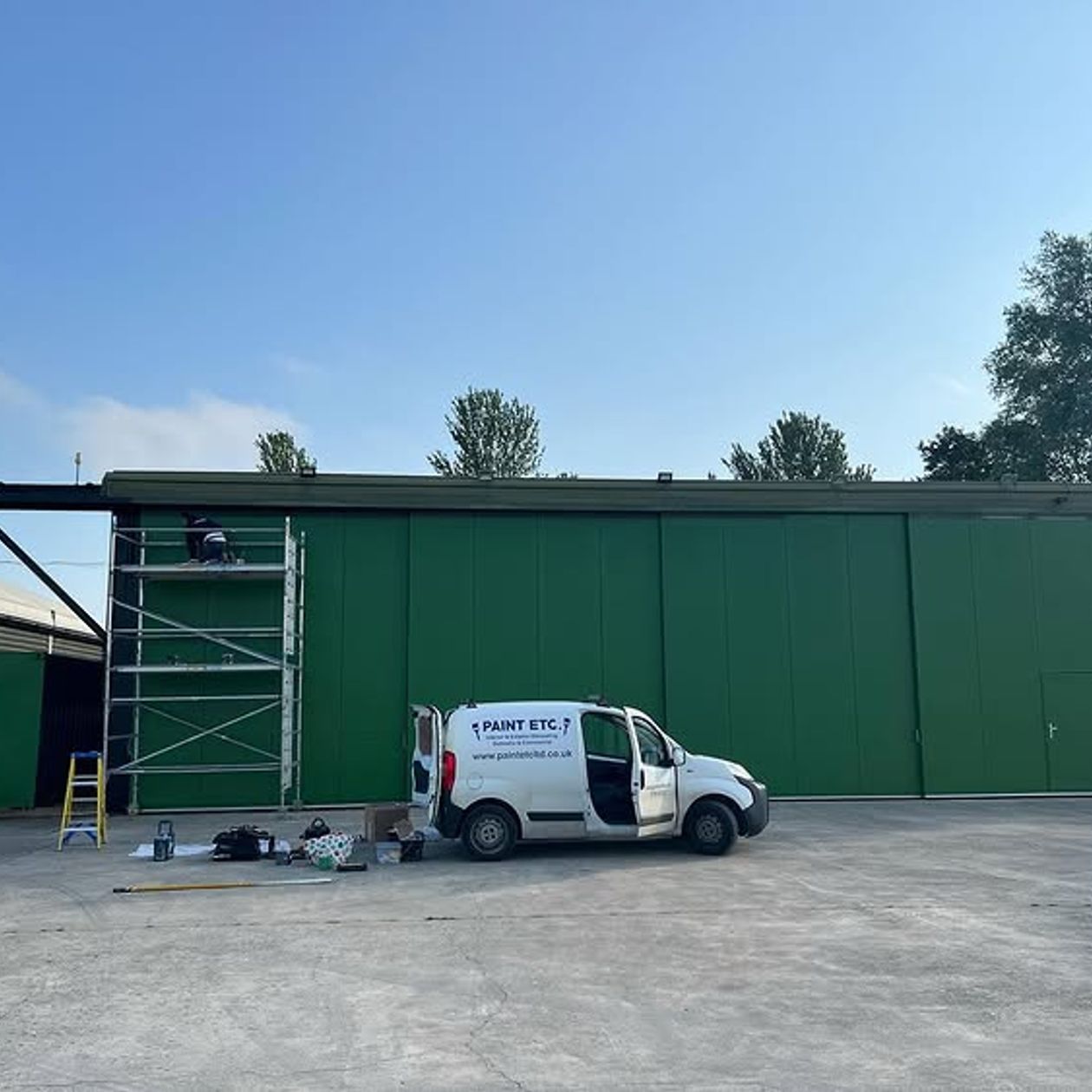a paint etc van parked outside a green storage yard